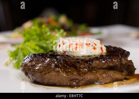 Nahaufnahme von Steak mit Herbed Butter und garniert auf Platte garniert Stockfoto