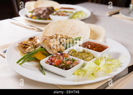 Gegrillte Chicken Fajitas mit Toppings auf Teller serviert im Restaurant Stockfoto