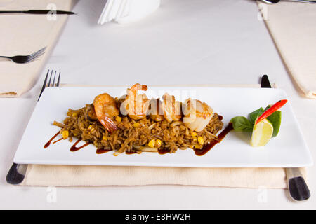 Garnelen und Jakobsmuscheln gebratener Reis auf quadratischen Platte im Restaurant serviert Stockfoto