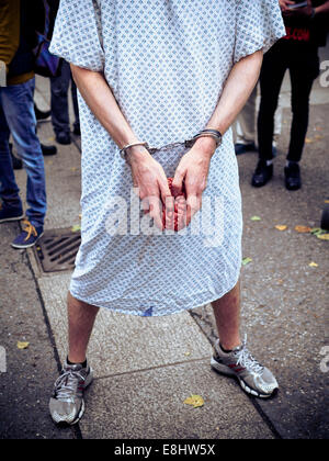 Mann in Krankenhemd mit Handschellen halten Kunststoff Gehirn. Kopf nicht gezeigt. Stockfoto