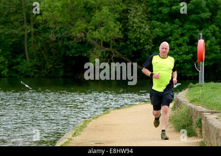 Mann, jogging am Weg um Waterloo See bei Roundhay Park, Leeds, West Yorkshire, Großbritannien. Stockfoto