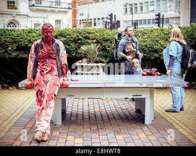 Zombie gelehnt Tischtennis-Platte, mit Zombie-Familie im Hintergrund. Stockfoto