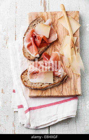 Bruschetta mit Käse und Schinken auf Brot auf blauem Hintergrund aus Holz Stockfoto