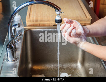 Frau wäscht Hände mit Seife in einer Küchenspüle Stockfoto