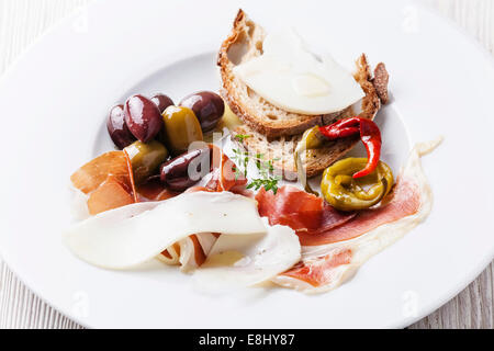 Vorspeise mit Schinken, Käse und Oliven auf weißen Teller Stockfoto