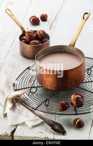 Kastaniensuppe im Kupferkessel mit gebratenen Kastanien auf blauem Hintergrund Textur Stockfoto