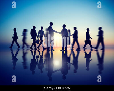 Zwei Geschäftsleute Handshaking gemeinsam mit ihren Kollegen Stockfoto