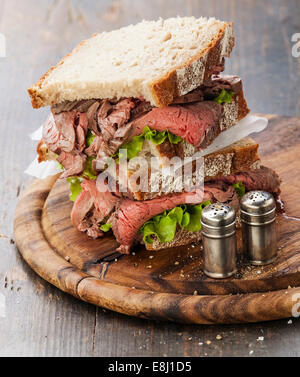 Roast Beef Sandwiches mit Salat auf Holzbrett auf dunklem Holz Stockfoto
