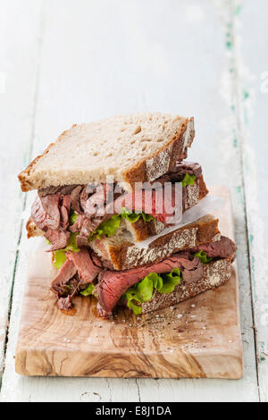 Roast Beef Sandwiches mit Salat auf Oliven Holz Schneidebrett Stockfoto