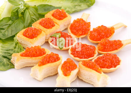 Roter Kaviar in Gebäck und Salat auf Teller. Stockfoto