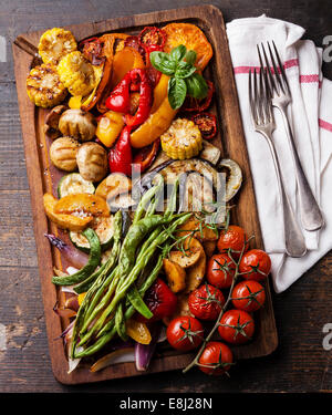 Gegrilltes Gemüse auf Schneidebrett auf dunklem Holz Stockfoto