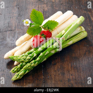 Dekorative Anordnung der Trauben von frischen grünen und weißen Spargelspitzen garniert mit Reife rote Erdbeeren Stockfoto