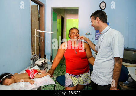 Französische Priester Etienne Kern besuchen ein Gemeindemitglied in ihrem Atelier in Alagados favela Stockfoto