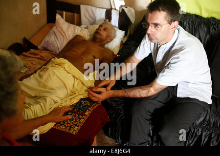 Französische Priester Etienne Kern besuchen ein sterbender Gemeindemitglied in Alagados favela Stockfoto