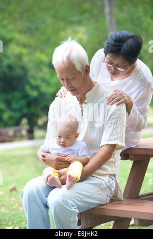 asiatische Großeltern spielen mit Baby Enkel im Außenbereich Stockfoto