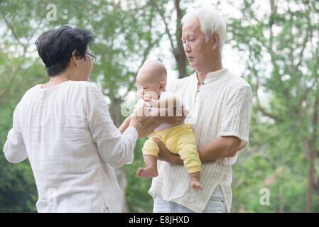 asiatische Großeltern spielen mit Baby Enkel im Außenbereich Stockfoto