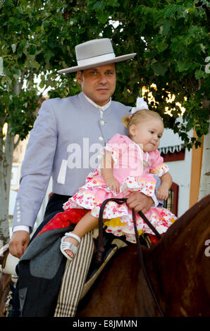 Mann auf Pferd Cordobes Hut in Tracht halten Mädchen, während der Feria von Fuengirola, Andalusien, Spanien. Stockfoto