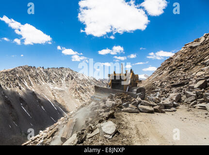 Planierraupe aufräumen Felsen auf dem Weg zum Khardung La Pass in Ladakh, Indien. Dies ist die höchste befahrbare Straße der Welt. Stockfoto