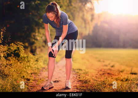 Junge Frau vor dem Training, Übungen Übungen, dehnen sie Muskeln auf einem Feldweg im Morgenlicht Stockfoto