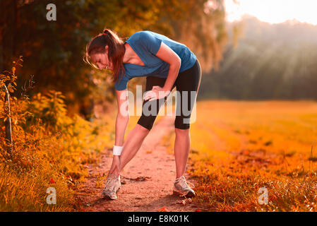 Junge Frau vor dem Training, Übungen Übungen, dehnen sie Muskeln auf einem Feldweg im Morgenlicht Stockfoto