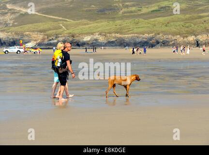 Ein paar zu Fuß einen Hund über Perranporth Strand Cornwall England uk Stockfoto