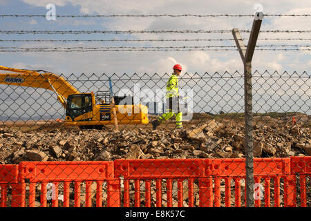 Hinkely Punkt C Somerset, UK. 9. Oktober 2014. Bauarbeiten am neuen EDF Energy Hinkley Point "C" Nuclear Power Station Schritte einen Gang höher, nachdem die Europäische Union die £ 24,5 Milliarden-Projekt genehmigt.  Ein Bauarbeiter Spaziergänge entlang der Perimater Zaun mit der aktuellen Hinkley Point 'B' Nuclear Power Station im Hintergrund. Stockfoto