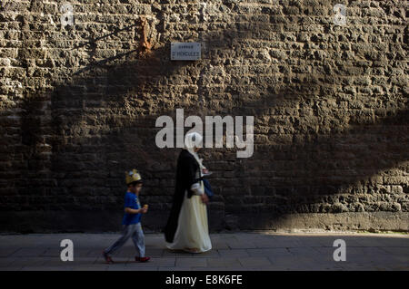 Barcelona, Spanien. 9. Oktober 2014. Im gotischen Viertel von Barcelona '' ‹'' ‹a Frau und ein Kind mit einer Krone, vorbei an der Seitenfassade (Hercules Street) von L'Esglesia Sant Just ist nach der Tradition die älteste Kirche der Stadt. © Jordi Boixareu/ZUMA Draht/Alamy Live-Nachrichten Stockfoto