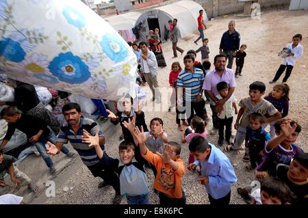 Suruc, Türkei. 9. Oktober 2014. Hunderte von Flüchtlingen, die nur eine Zeltstadt in Suruc, Türkei ankamen, erhalten Decke und Kleidung von einer Verteiler-Lkw. Die waren kommen von Hilfsorganisationen und NGOs arbeiten mit der türkischen Regierung. Schweren Kämpfen an der Grenze zwischen der Türkei und Syrien sieht mehr Flüchtlinge gegenüber Syrien in die Türkei zu überfluten. Sie sind Settleing in unfertigen Zeltstädte. Die kurdischen syrische Flüchtlinge aus Kobani haben die islamischen Staat Kämpfer flohen und Leben in Felder neben Stromnetze und auf offener Straße. Bildnachweis: ZUMA Press, Inc./Alamy Live-Nachrichten Stockfoto