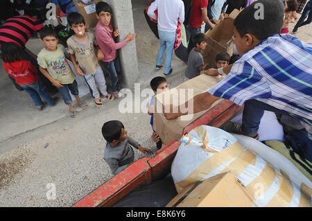 Suruc, Türkei. 9. Oktober 2014. Hunderte von Flüchtlingen, die nur eine Zeltstadt in Suruc, Türkei ankamen, erhalten Decke und Kleidung von einer Verteiler-Lkw. Die waren kommen von Hilfsorganisationen und NGOs arbeiten mit der türkischen Regierung. Schweren Kämpfen an der Grenze zwischen der Türkei und Syrien sieht mehr Flüchtlinge gegenüber Syrien in die Türkei zu überfluten. Sie sind Settleing in unfertigen Zeltstädte. Die kurdischen syrische Flüchtlinge aus Kobani haben die islamischen Staat Kämpfer flohen und Leben in Felder neben Stromnetze und auf offener Straße. Bildnachweis: ZUMA Press, Inc./Alamy Live-Nachrichten Stockfoto