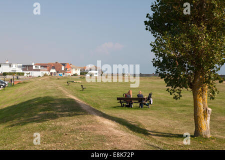 Zwei Frauen auf einer Bank auf dem Rasen neben der Strandpromenade, Selsey, West Sussex Stockfoto