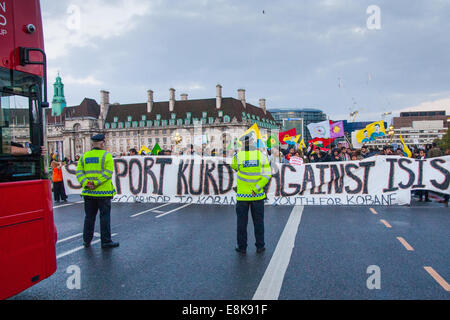 London, UK. 9. Oktober 2014.  Polizisten beobachten, wie Demonstranten Westminster Bridge, blockieren da Resultate von Kurden gegen ISIS und fordern demonstrieren, daß Großbritannien und der Türkei ihnen helfen sich gegen die Dschihad-Bewegung zu verteidigen. Bildnachweis: Paul Davey/Alamy Live-Nachrichten Stockfoto
