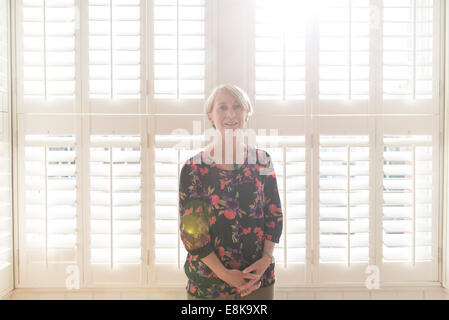 Eine Business-Frau / Mutter mit kurzen Haaren steht durch Jalousien in interessanten Licht Stockfoto