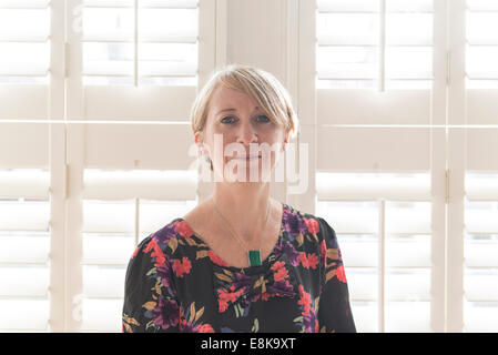 Eine Business-Frau / Mutter mit kurzen Haaren steht durch Jalousien in interessanten Licht Stockfoto