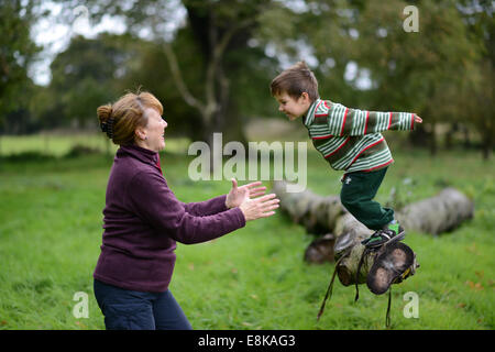 Kind Kinder junge Outdoor-Spaß mit Oma in die Arme springen trust vertrauensvolle Uk Stockfoto