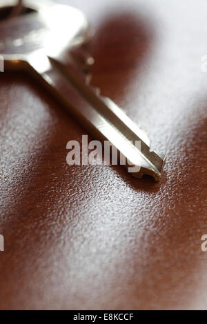 Nahaufnahme eines Schlüssels auf dem Tisch. Finger nach dem Schlüssel zu erreichen ihre Schatten auf die Kunststoffoberfläche des Tisches. Stockfoto