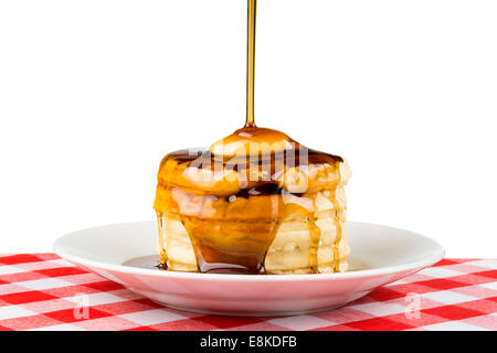 Süßer Ahornsirup über einen heißen, frisch gebutterte Stapel Waffeln gegossen wird. Stockfoto