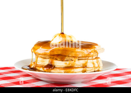 Süßer Ahornsirup über einen heißen, frisch gebutterte Stapel von Pfannkuchen gegossen wird. Stockfoto