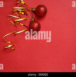 Roter Hintergrund mit Christbaumkugeln und Streamer in einer Ecke Stockfoto