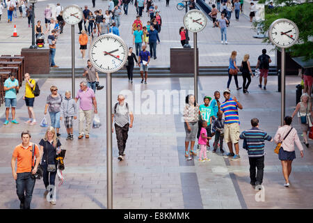 Menschen in einem Quadrat mit Uhren, Canary Wharf, Docklands, London, England, Vereinigtes Königreich Stockfoto