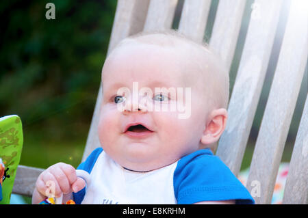 Baby-sitting auf einem Gartenstuhl im Garten Stockfoto