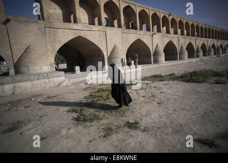 Isfahan, der Iran. 9. Oktober 2014. 9. Oktober 2014 - Isfahan, der Iran - eine iranische Frau Spaziergänge am Fluss ausgetrockneten Zayanderood verschleiert als die alten Si-o-Seh-Pol (33-Brücke), in der Stadt Isfahan 450 km (281 Meilen) südlich von Teheran. Morteza Nikoubazl/ZUMAPRESS © Morteza Nikoubazl/ZUMA Draht/Alamy Live-Nachrichten Stockfoto