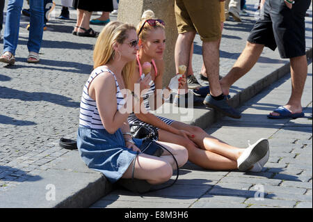 Zwei junge Frauen im Sommerkleidung mit Zapfen von Eis sitzt auf dem Bürgersteig, Prag, Tschechische Republik. Stockfoto