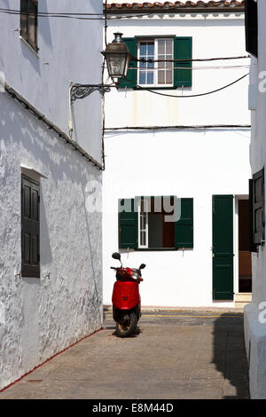 Roter Roller parkten in einer Seitengasse gewaschene weiße Gebäude mit grünen Fensterläden aus Holz, Formelis, Menorca, Spanien Stockfoto