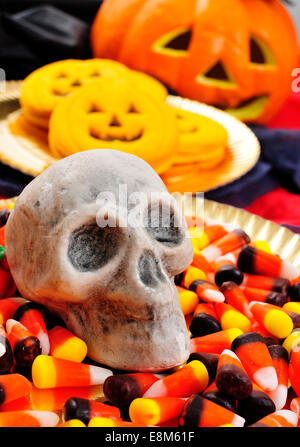 Nahaufnahme einer Platte mit Halloween Süßigkeiten und ein Schädel und einige Kürbis-förmigen Cookies mit beängstigend Ornamenten im Hintergrund, s Stockfoto