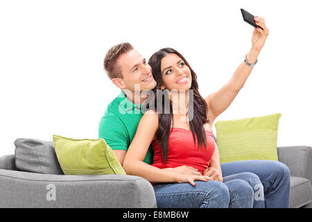 Frau, die eine Selfie mit ihrem Freund sitzt auf einem Sofa isoliert auf weißem Hintergrund Stockfoto