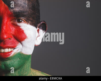 Mann und sein Gesicht gemalt mit Palästina-Flagge auf dunklem Hintergrund isoliert Stockfoto