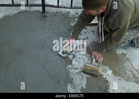 Arbeiter glättet eine Skim-Beschichtung von Zement auf alte Treppe. Stockfoto