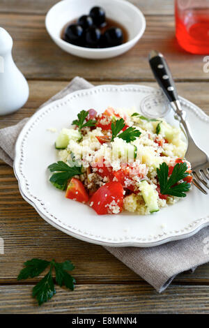 Salat mit gekochten Couscous und Gemüse auf einem weißen Teller, nahrhaftes Essen Stockfoto