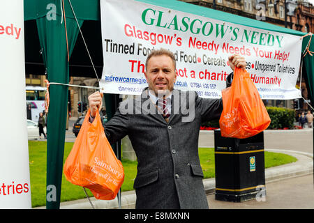 Glasgow, Schottland. 11. Oktober 2014. Andrew Carnegie, im Alter von 45 aus Tollcross in Glasgow, wer die Tafel Nächstenliebe, die einen Stall in der George Square, das Stadtzentrum von Glasgow außerhalb der City Chambers mit der Absicht, Beiträge zu sammeln und auch Aufmerksamkeit auf soziale Ungleichheit und die Bedürfnisse der Armen 'Glasgows Needy' einrichten einrichten. Mehrere Passanten-durch dazu beigetragen, seine Liebe durch Abgabe Taschen von Lebensmitteln, einschließlich Colin Boyd, im Alter von 38 Jahren. Geschäftsführer von Kilwinning. Bildnachweis: Findlay/Alamy Live-Nachrichten Stockfoto