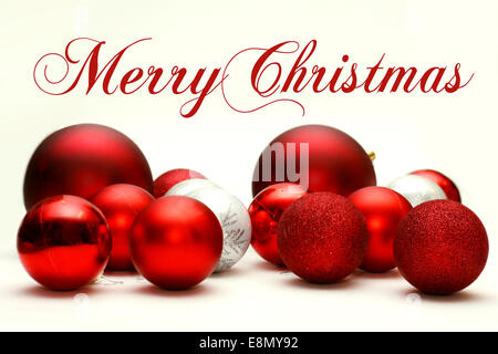 Eine Sammlung weiß und rot funkelnden Christbaumkugeln Birne sind auf einem weißen Hintergrund, mit kursiven Text Merry Chris verstreut. Stockfoto